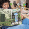 Femme assise confortablement à un bureau lisant le magazine Polymère & Co No38 Voyage en Féerie